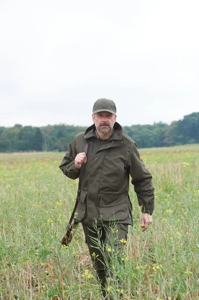 Jäger auf Feld mit grüner Jagdjacke